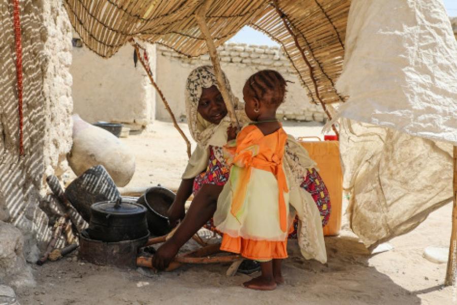 Youssoura regarde sa maman préparer le feu pour la cuisine.